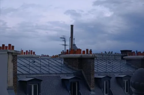 A brick chimney on a tiled roof.